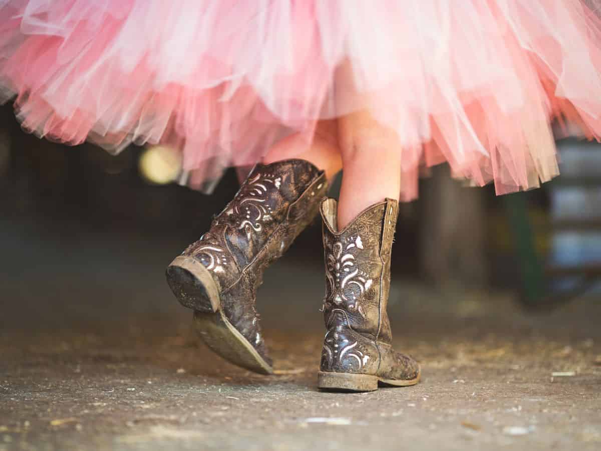 A girl wearing a pink tutu and cowboy boots.