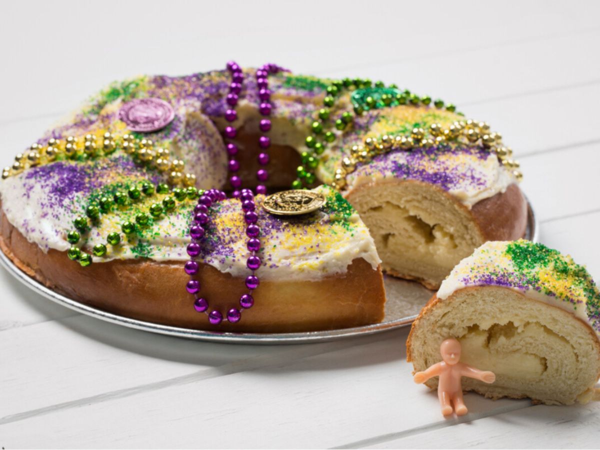 A king cake decorated with beads and purple, gold, and green icing.