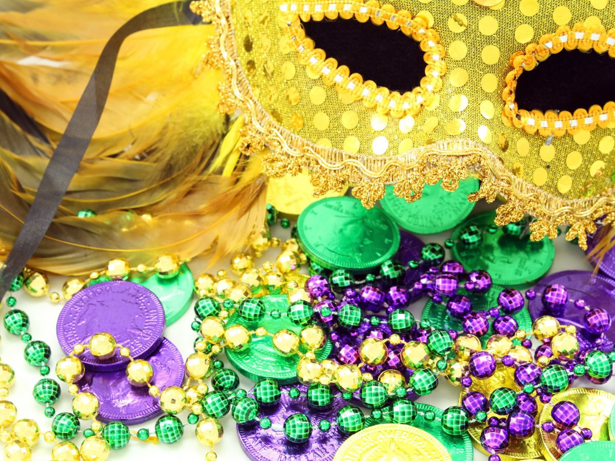 Mardi Gras mask, beads, and doubloons on a white background.