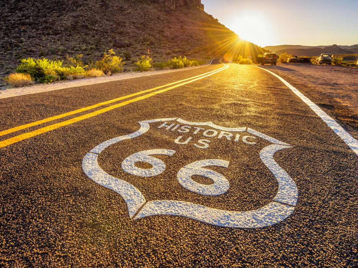 Route 66 marker painted on a stretch of the iconic highway at sunset.